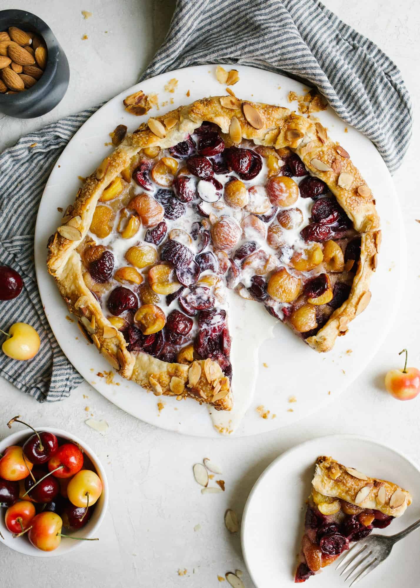 Cherry Almond Galette by Wood and Spoon. This is an all-butter pie crust filled with seasonal rainier and dark cherries and an almond meal frangipane filing. Top with ice cream and serve wedge slices as a summer dessert perfect for picnics and parties. Find more about this simple pie recipe on thewoodandspoon.com