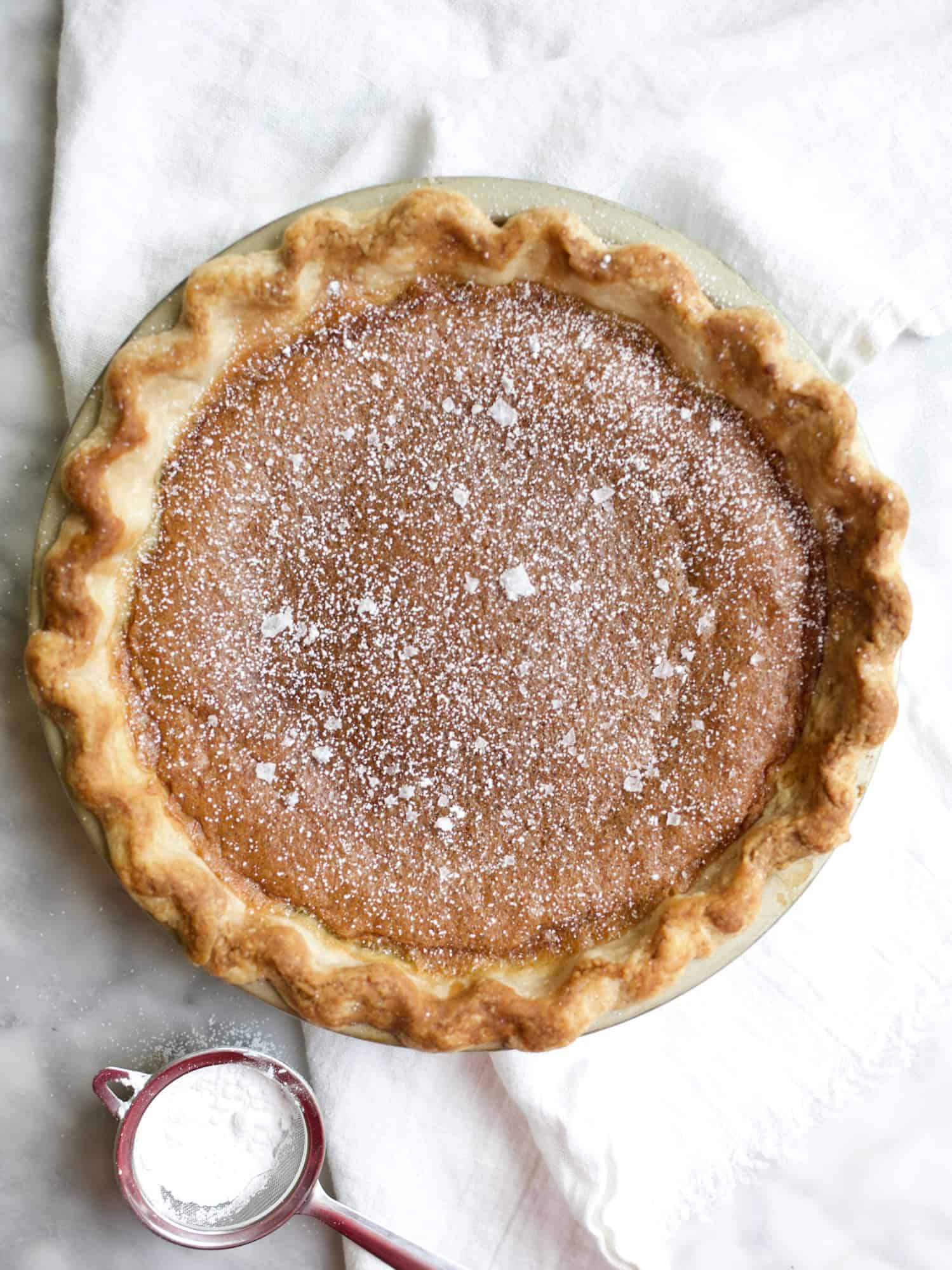 Brown Butter Bourbon Chess Pie by Wood and Spoon blog. This is a brown sugar, brown butter, and bourbon Southern chess pie. this is a gooey pie with a flaky homemade crust. The pie serves a crowd, is perfect for holidays and fall, and finishes with flakes salt. Learn how to make homemade chess pie on thewoodandspoon.com