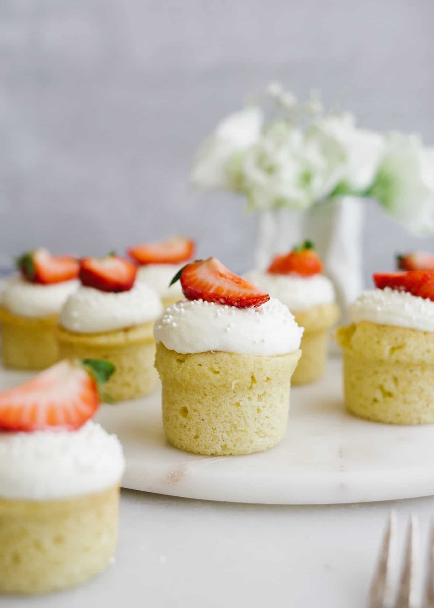 Mini Victoria Cakes by Wood and Spoon. These are mini sponge cupcakes with a strawberry jam filling and whipped cream topping. These are fancy looking little two bite treats perfect for tea parties. Read all about these cute summer desserts on thewoodandspoon.com