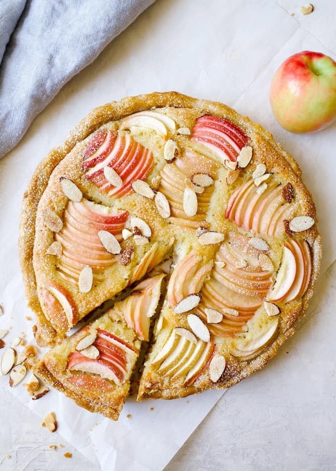 Apple Frangipane Tart by Wood and Spoon blog. This is an elegant holiday tart with a flaky pie crust, and almond filling and beautiful apples on top. Served with a glass of wine this is the French treat your holiday guests will go crazy for! This fancy dessert is made in a tart pan and easily serves a crowd. Find out more about the recipe on thewoodandspoon.com