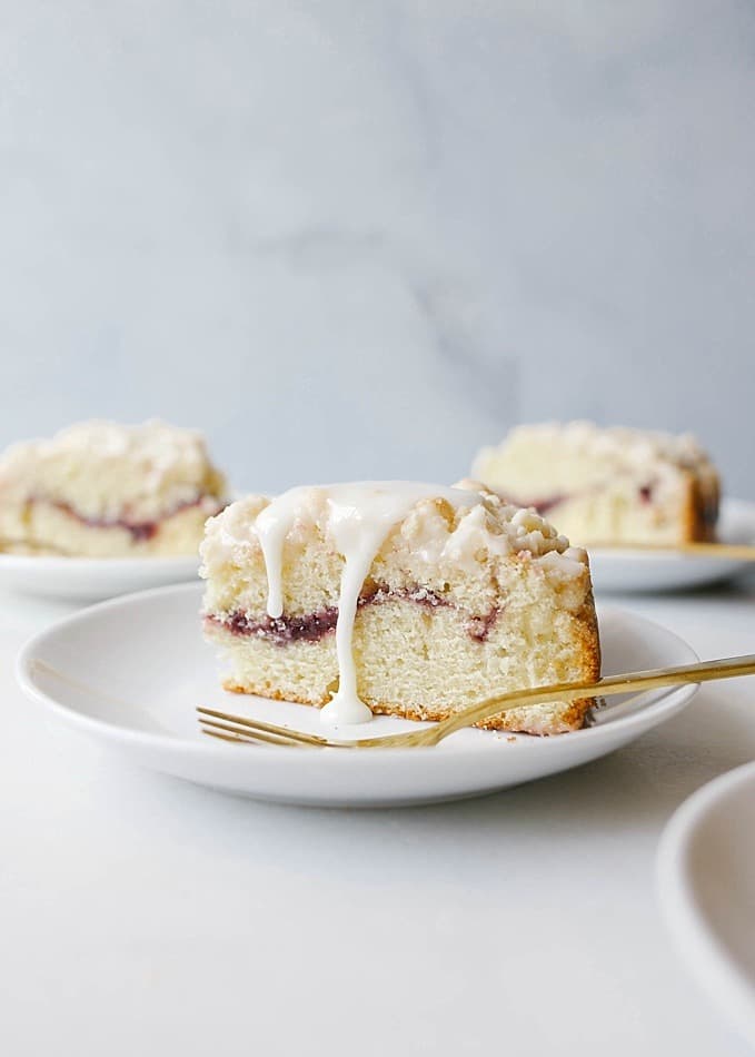 Lemon Berry Crumb Cake recipe by Wood and Spoon blog by Kate Wood. This is a simple lemon zest flavored spring time single layer cake filled with a tart raspberry jam and topped with a simple shortbread crumble. The cake bakes up into an easy dessert that can also serve as a breakfast of brunch item. Pour on a thick powdered sugar lemon glaze for extra decoration. Find the recipe for this Easter favorite on thewoodandspoon.com