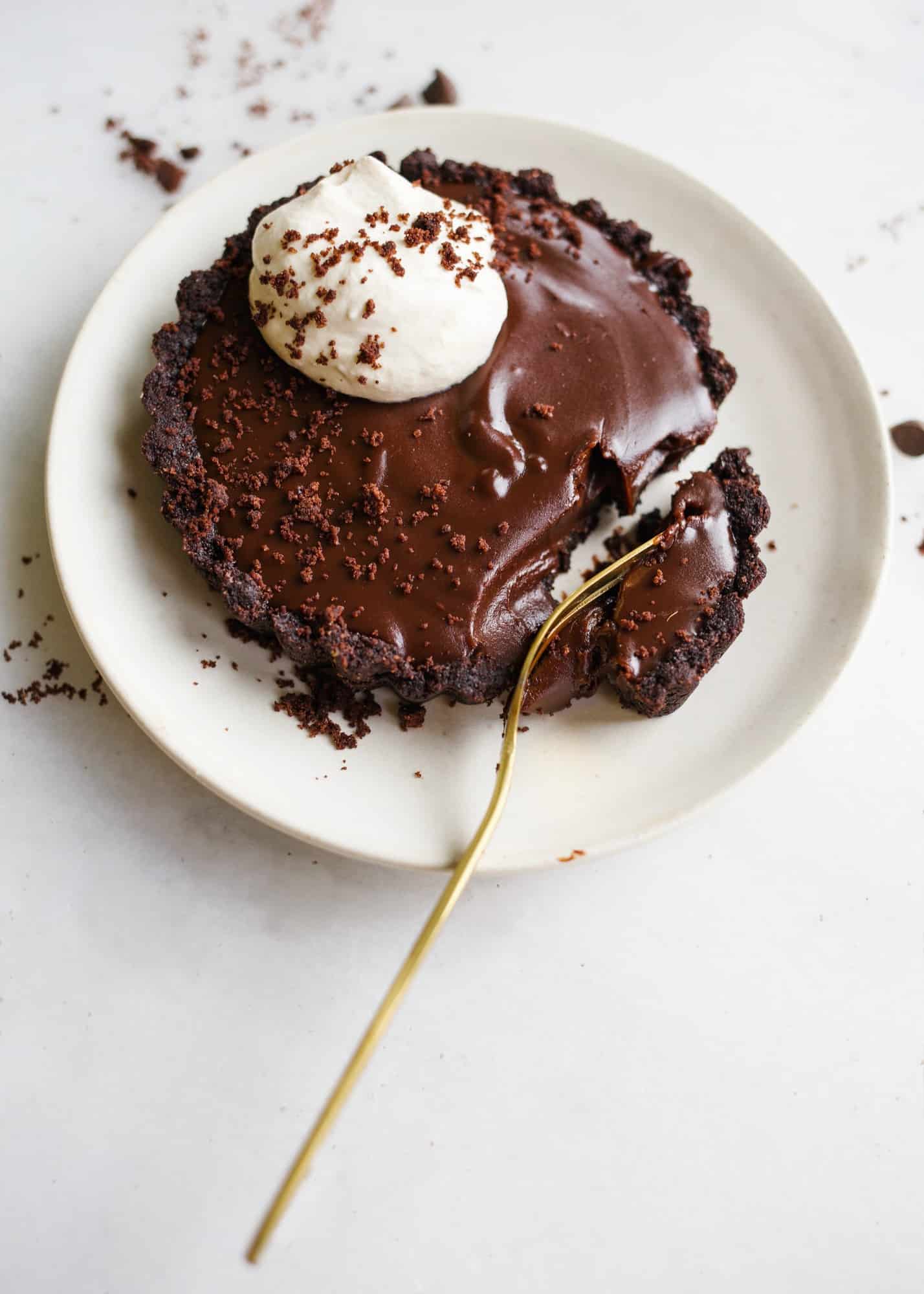 Espresso Chocolate Tarts by Wood and Spoon blogs. These tarts have a cocoa powder and espresso shortbread crust and a rich and buttery semisweet chocolate ganache filling. To top them, a simple espresso whipped cream is added! These tarts make a great festive individual dessert but each one can easily serve as a dessert for two as well! Learn how to make homemade chocolate tarts on thewoodandspoon.com