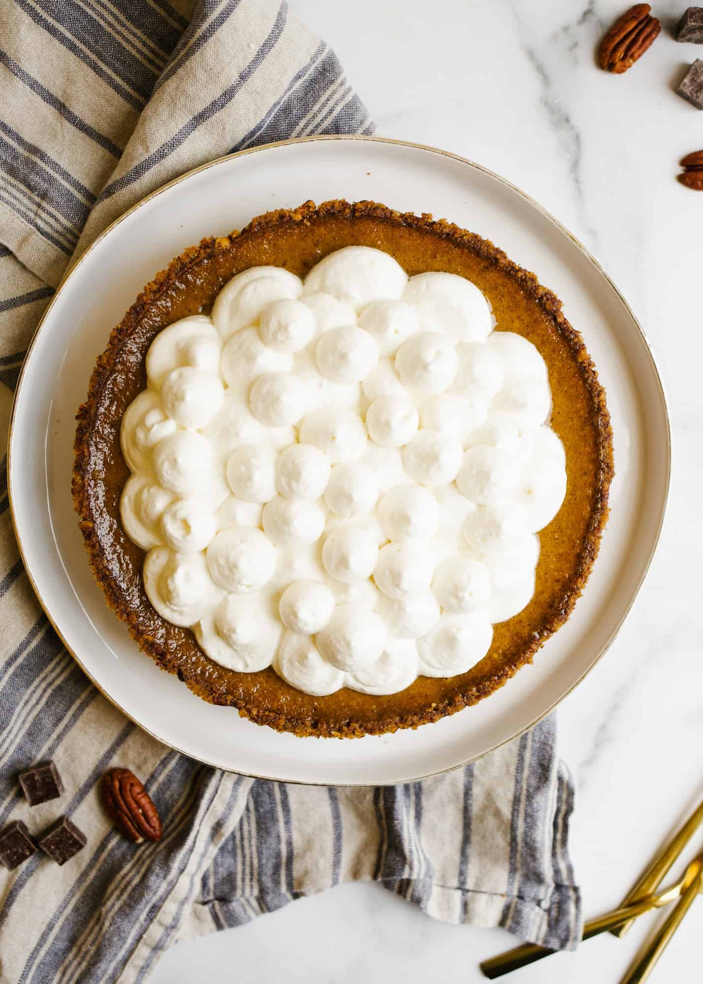 Black Bottom Pumpkin Pie is a creamy baked fall custard pie with a fudge chocolate bottom and pecan pie crust ready made from Diamond nuts. Topped with whipped cream and chocolate shavings this is a great holiday / Thanksgiving alternative for chocolate lovers. This pie is a simple one to make and bakes up without cracks! Learn more about the recipe on thewoodandspoon.com