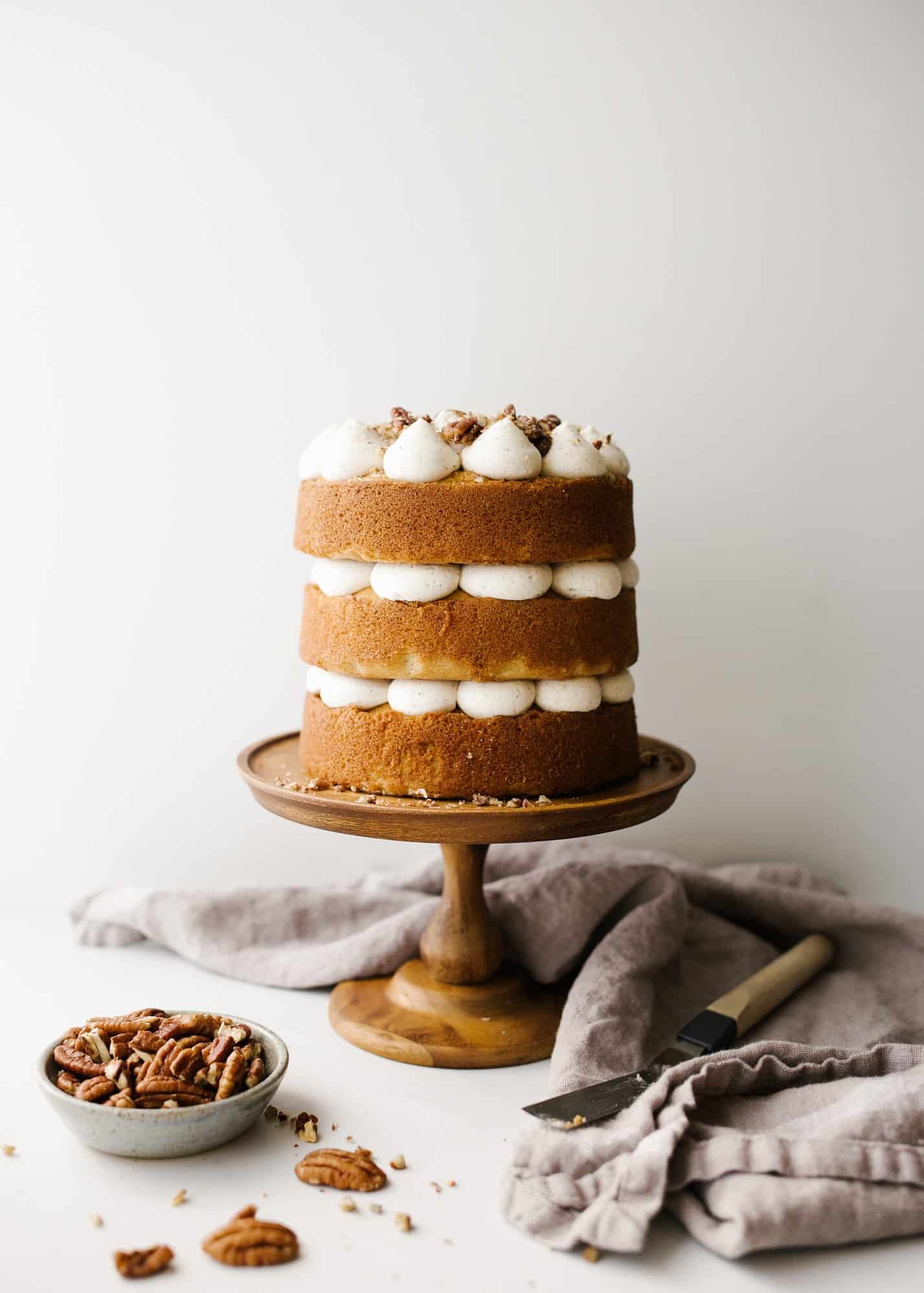 Brown Butter Cake with Candied Pecans by Wood and Spoon blog. This is a simple brown sugar mini layer cake with brown butter buttercream and candied pecans throughout. This small batch recipe makes a small layer cake to serve just a few and makes for a festive offering for fall, winter, and holiday celebration desserts. Learn how to candy nuts and stack a naked layer cake on thewoodandspoon.com